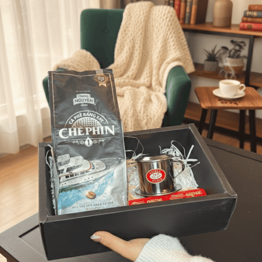Box with a coffee package and other items on a table in a cozy room.