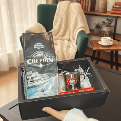 Box with a coffee package and other items on a table in a cozy room.